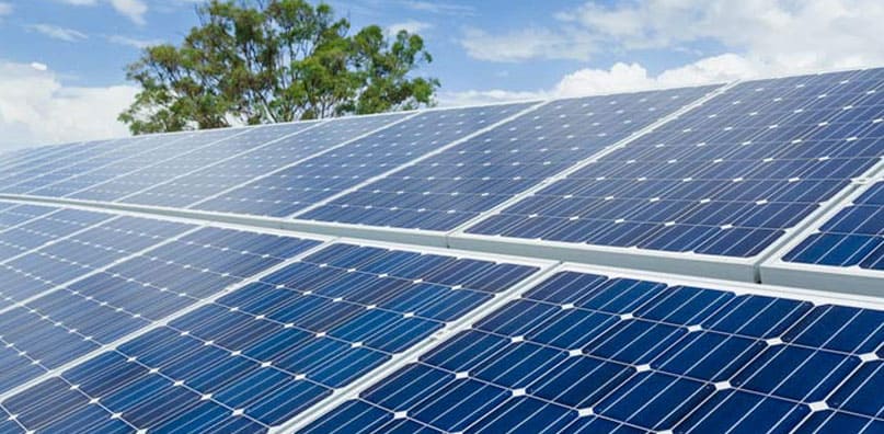 Rows of dark blue solar panels beneath a bright sky